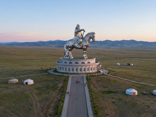A photograph of the massive Genghis Khan Equestrian Statue complex on the Mongolian steppe during sunrise.