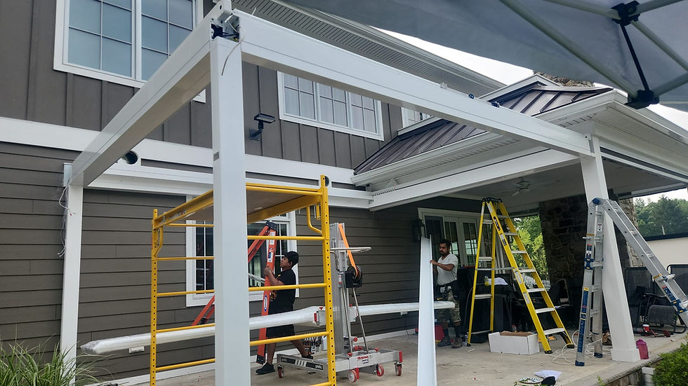 Privlux Workers install a white framed pergola on a brown house. Yellow scaffolding and ladders are around the area. The mood is industrious.