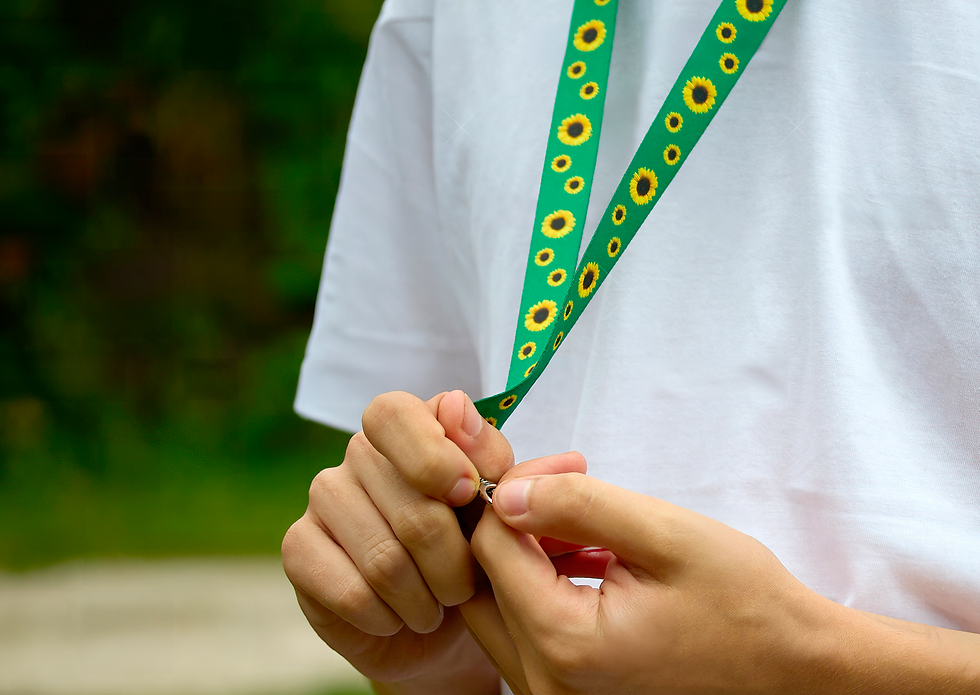 Young boy fiddling with a Hidden Disability Sunflower lanyard around his neck.