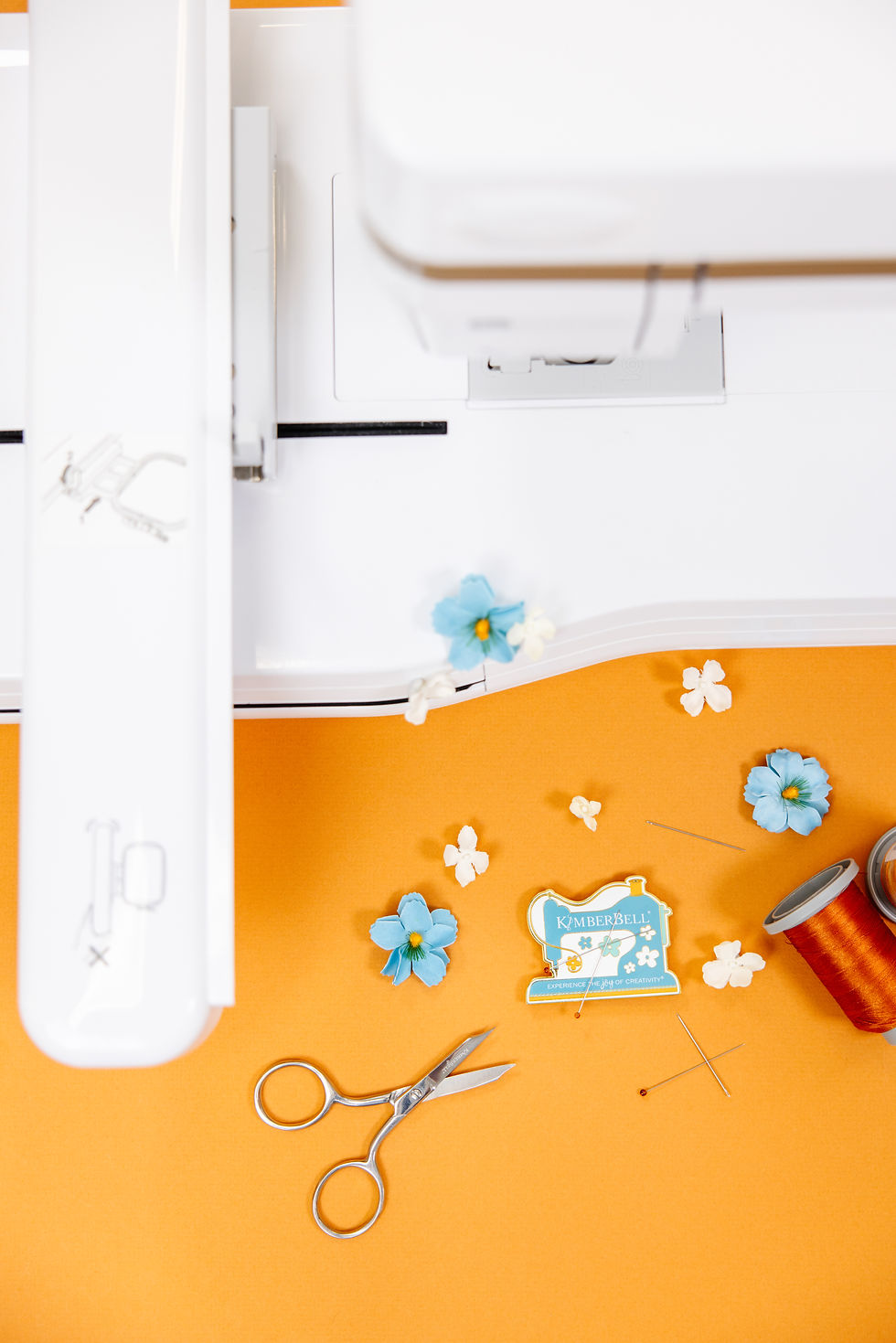 White sewing machine and sewing supplies on an orange background close up.