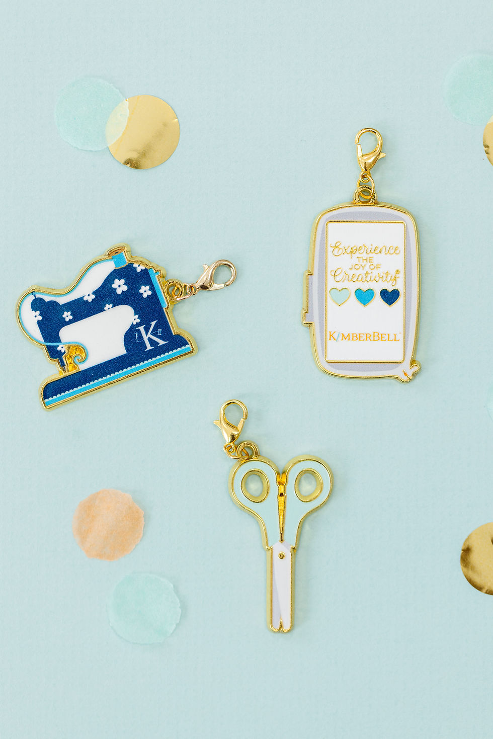 Sewing machine, scissors, and embroidery hoop charms on a light blue background