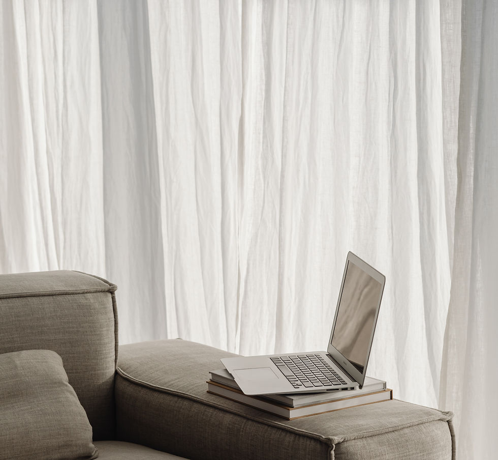 A laptop and books on a couch in a casual working environment