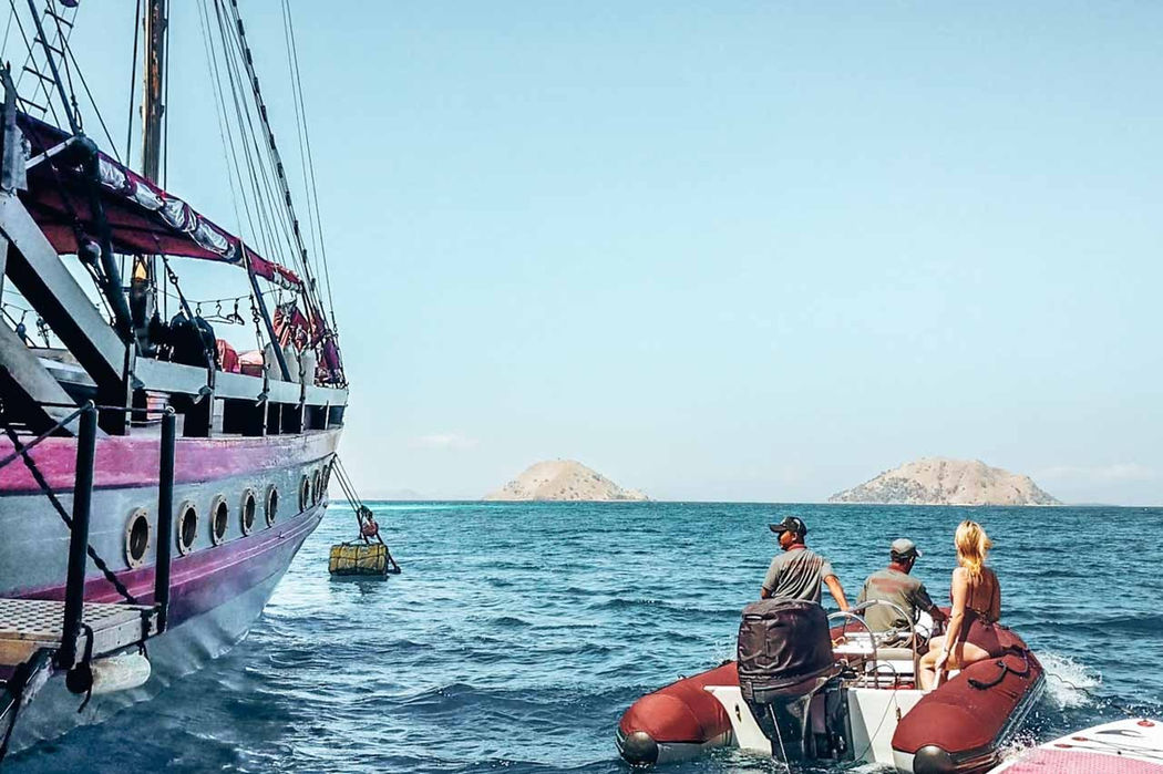 Guests boarding Mantamae yacht from tender boat in calm sea