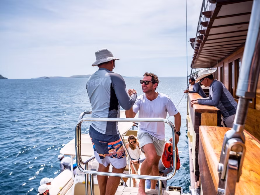 Yacht crew assisting guests on deck during a private Indonesian charter, ensuring comfort and seamless service at sea