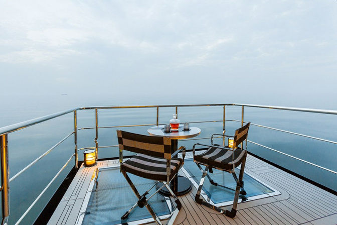 Private balcony with teak chairs and sea views on a yacht suite
