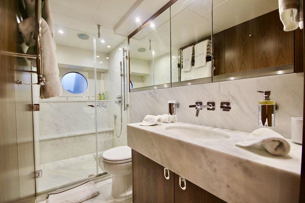 Luxury yacht bathroom with marble sink, glass shower, and porthole window
