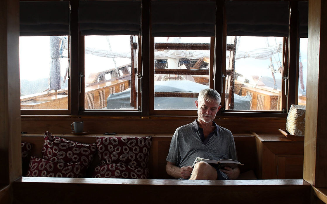 Guest relaxing in lounge area with wooden interiors aboard Tiare yacht