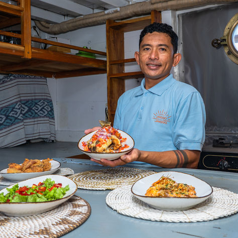 Private chef preparing gourmet dining on deck of a luxury Phinisi yacht in Indonesia during a Navélia charter