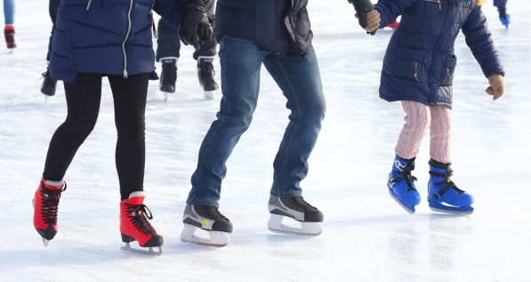 Three people ice skating hand-in-hand on a rink. They wear blue coats and colorful skates. Bright, sunny setting with an energetic vibe.