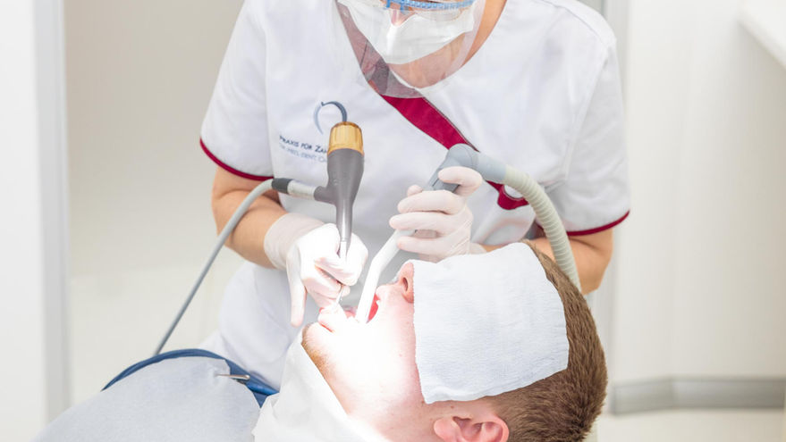 Zahnärztin behandelt Patienten mit Instrumenten im Mund in Zahnarztpraxis.