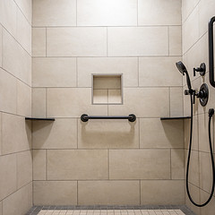 Tiled shower wall with a recessed niche and horizontal grab bar