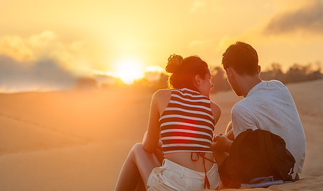 Ein Foto von einem Pärchenn das harmonisch im Sonnenuntergang am Strand sitzt. Ein mögliches Ergebnis der Paartherapie Rosenheim.