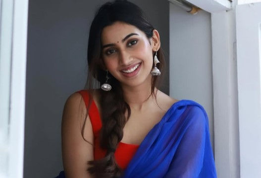 Smiling Telugu American woman in a blue and red saree.