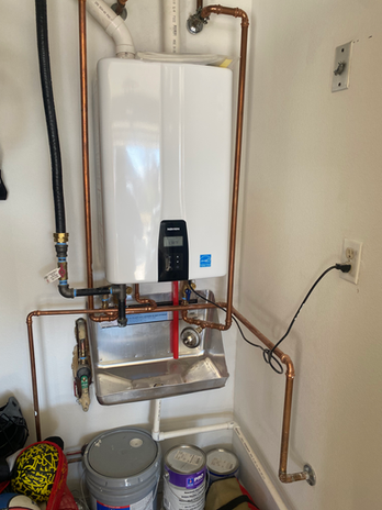 Navien tankless water heater with copper piping and utility sink in a garage