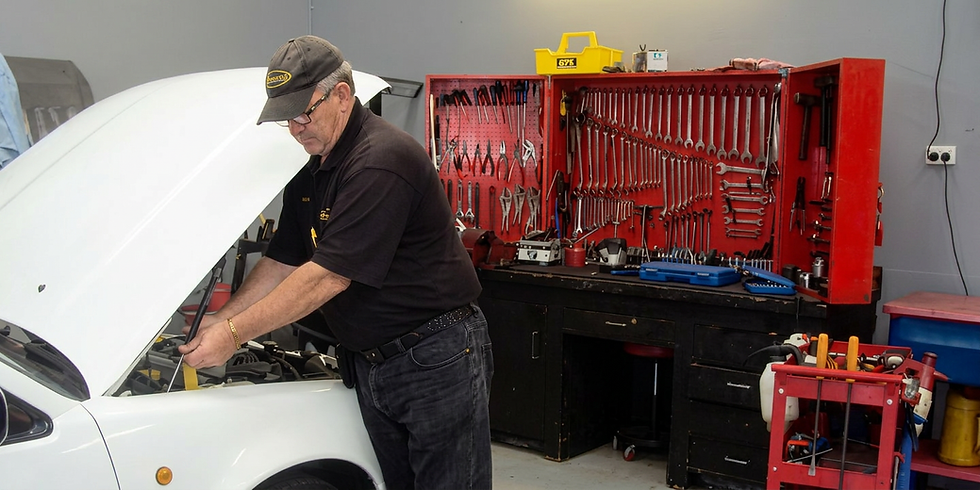 Mechanic inspecting a white car engine in an auto shop.