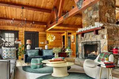 Skypine Lodge Living Room central stone fireplace vaulted log ceiling beams modern design chandelier
