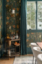 Dining room with custom velvet drapery in deep teal, paired with floral wallpaper and matching trim. Features a vintage brass bar cart, neutral upholstered dining chairs, and layered textures. A moody, sophisticated interior by Asha Maia Design highlighting rich color and tailored window treatments. Asha Maia Design creates timeless interiors in Arlington, Virginia, Alexandria, Virginia, and Birmingham, Michigan.