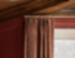 Close-up of custom 2-finger Euro pleat drapery on a brass rod, featuring patterned fabric in warm clay tones. Designed by Asha Maia Design as part of a layered window treatment with woven Roman shades. This refined drapery style blends traditional and modern elements. Asha Maia Design serves Arlington, Virginia, Alexandria, Virginia, McLean, Virginia, and Birmingham, Michigan.