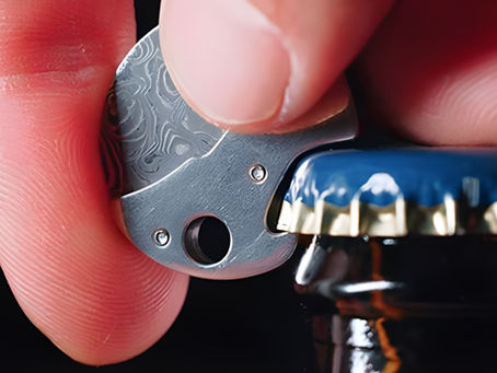 Nano-sized Sting bottle opener and Damascus steel blade being used to open a classic glass bottle; perfect minimalist gift for him.