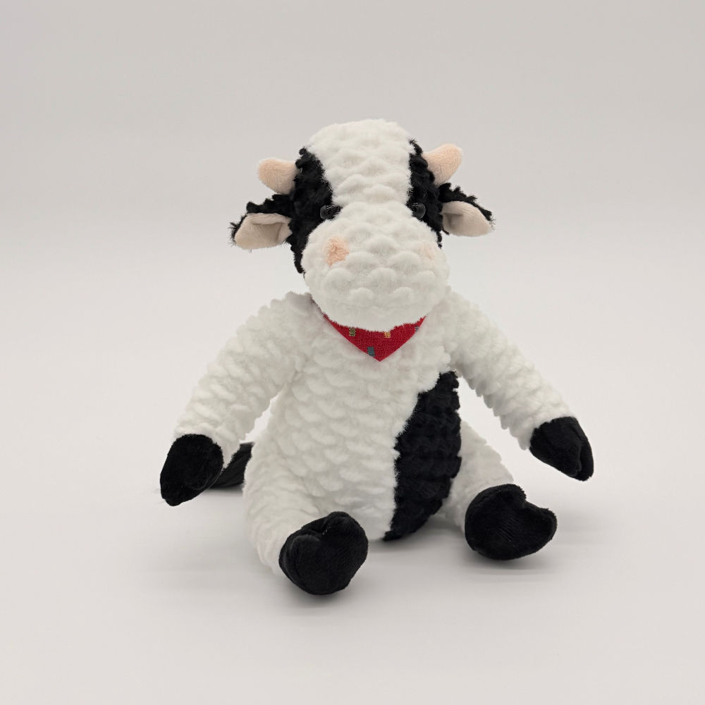 Front view Huggable Toys Casey Cow with black and white patches, embroidered eyes, soft horns, and a red tie around his neck