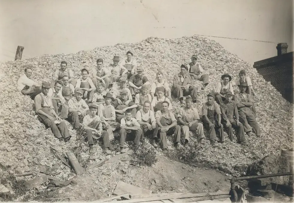 Factory workers sit atop a massive pile of waste shells, a byproduct of button manufacturing. Washington County Historical Society / Twin Cities Pioneer Press