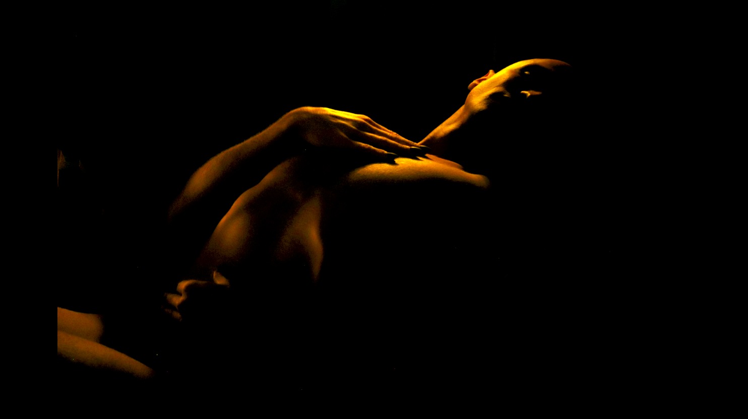 Performer moving their body in low stage lighting