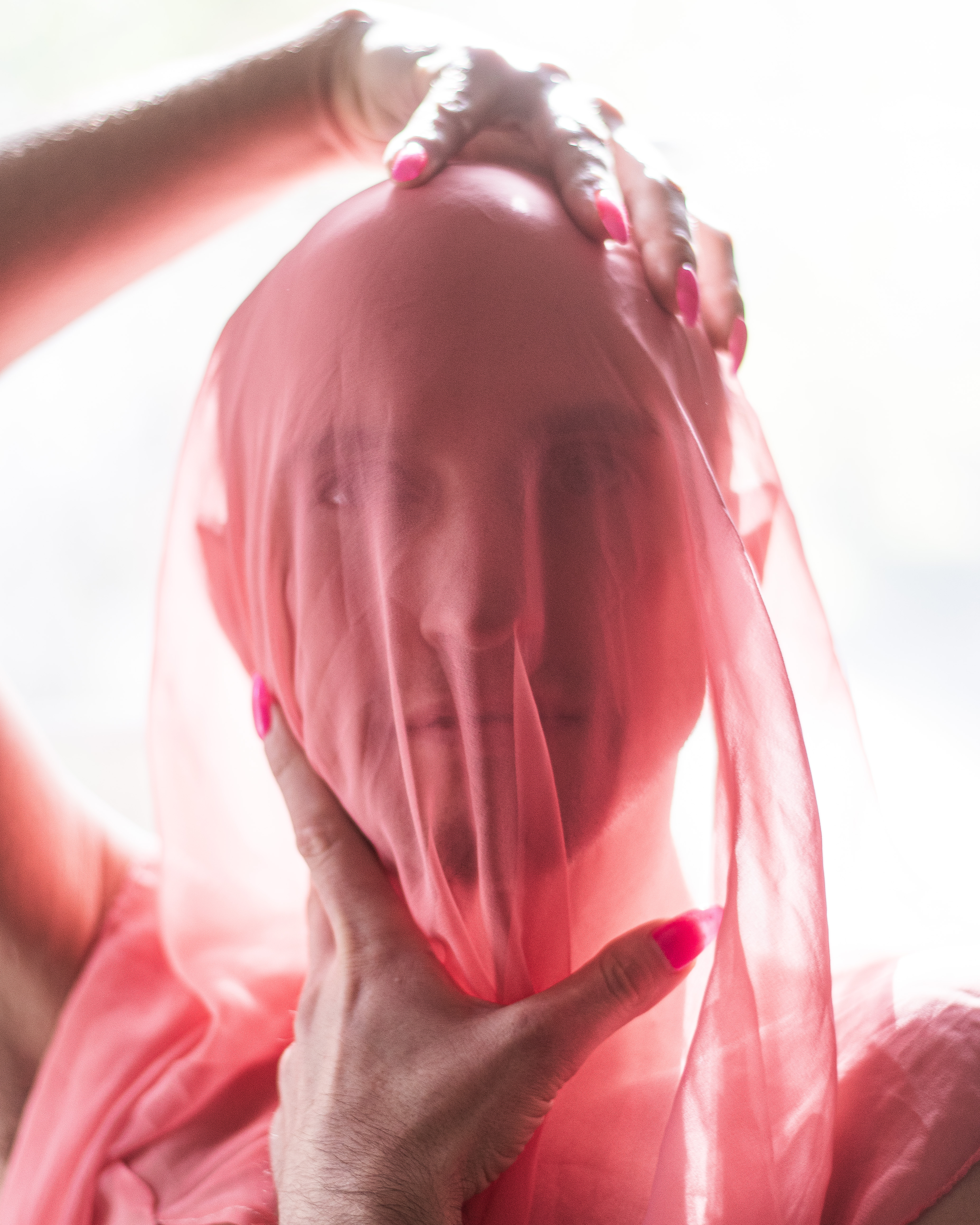 Pink sheer fabric, pink nails, and white backlight in a portrait by Justin Anantawan