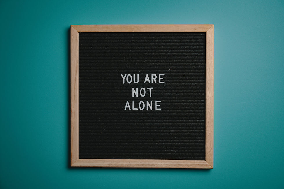 Framed black felt letter board on teal wall reads YOU ARE NOT ALONE, conveying support.