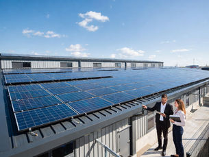Chef d’entreprise et ingénieur énergie discutant devant une grande installation de panneaux solaires photovoltaïques sur la toiture d’un bâtiment industriel moderne, documents et tablette affichant projet solaire, environnement industriel propre et moderne, panneaux solaires brillants au soleil, photographie professionnelle ultra réaliste d’infrastructure énergétique durable et énergie renouvelable pour entreprises B2B
