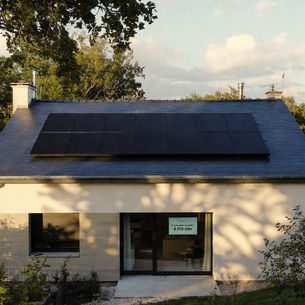 Maison contemporaine à Saint-Cyr-sur-Loire en Indre-et-Loire avec toiture en ardoise équipée de 18 panneaux solaires photovoltaïques noirs en surimposition, installation solaire résidentielle en autoconsommation, quartier arboré des hauteurs de Tours nord et lumière dorée de fin de journée.