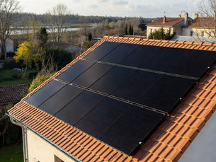 Maison individuelle à Meung-sur-Loire dans le Loiret avec toiture en tuiles plates équipée de 14 panneaux solaires photovoltaïques noirs en surimposition, installation solaire résidentielle en autoconsommation avec jardin et vue sur la Loire, lumière ensoleillée de fin d’après-midi en Centre-Val de Loire.