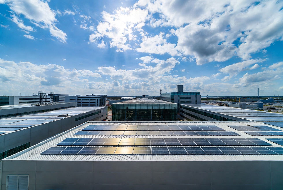 Grande zone industrielle française avec plusieurs bâtiments d’entreprise et usine moderne équipés de panneaux solaires photovoltaïques sur les toitures, lignes de production visibles à travers baies vitrées, panneaux solaires brillants sous soleil, environnement industriel propre et moderne, photographie ultra réaliste d’architecture industrielle durable et énergie renouvelable pour entreprises