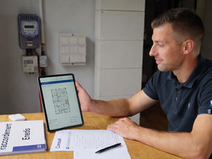 Conseiller solaire Mon Kit Énergie en rendez-vous à domicile en Centre-Val de Loire, présentant sur tablette une analyse de toiture et une estimation de production photovoltaïque, avec dossier de raccordement électrique et contrôle Consuel, compteur et tableau électrique en arrière-plan, ambiance professionnelle et rassurante.