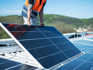 Installateur RGE posant des panneaux solaires sur une toiture.