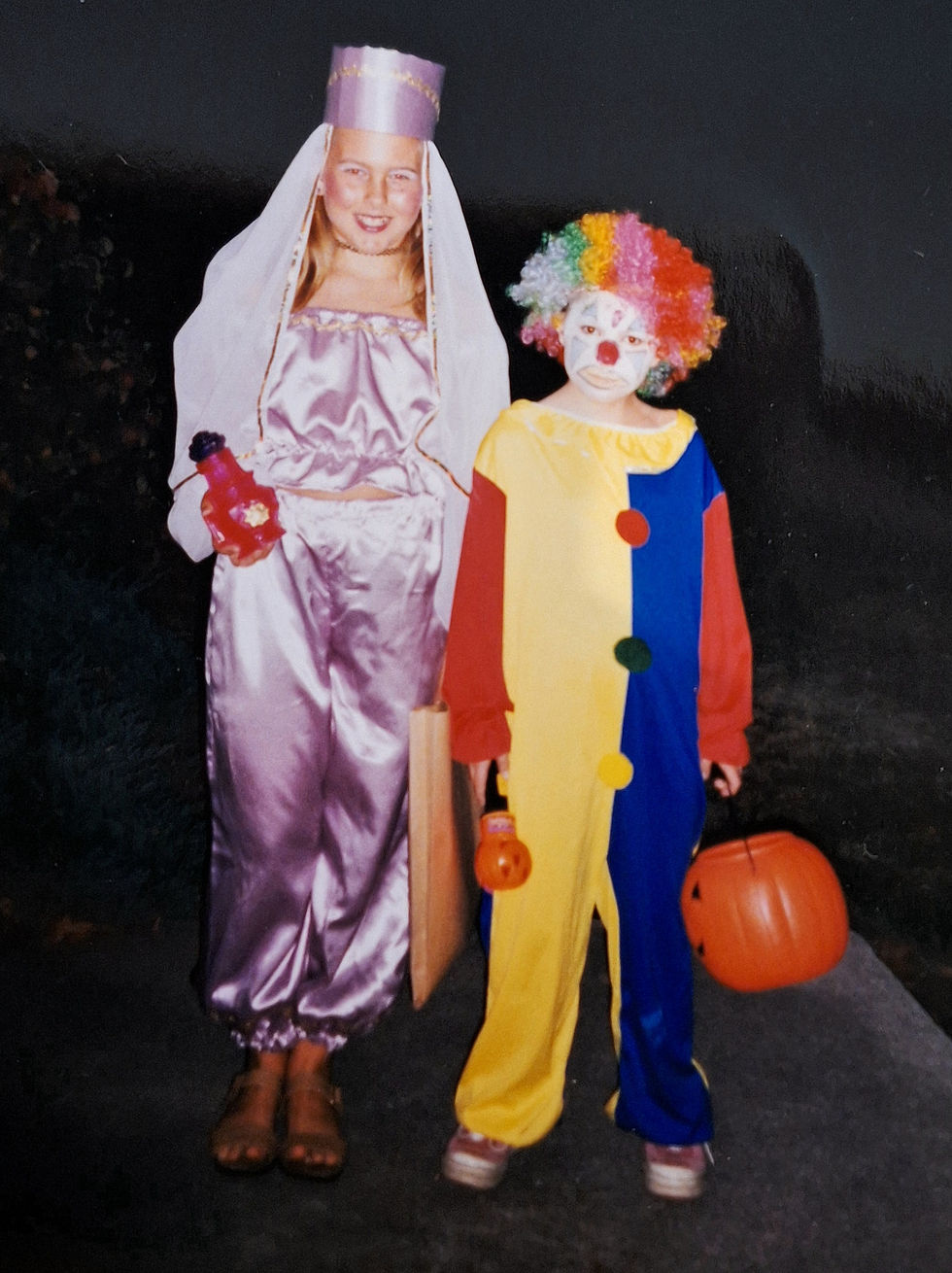 Two girls in Halloween costumes. Purple "I Dream of Genie" and orange and black "Spiderella".
