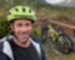 Jayson smiling somewhere in the back country with his lime green bike and lime green bike helmet because safety first.