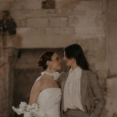 Photo of a couple on their wedding day, one in a dress and one in a suit. Faces close and looking lovingly at each other. Natural, storytelling photography by Suffolk photographer Mikaela Jade.