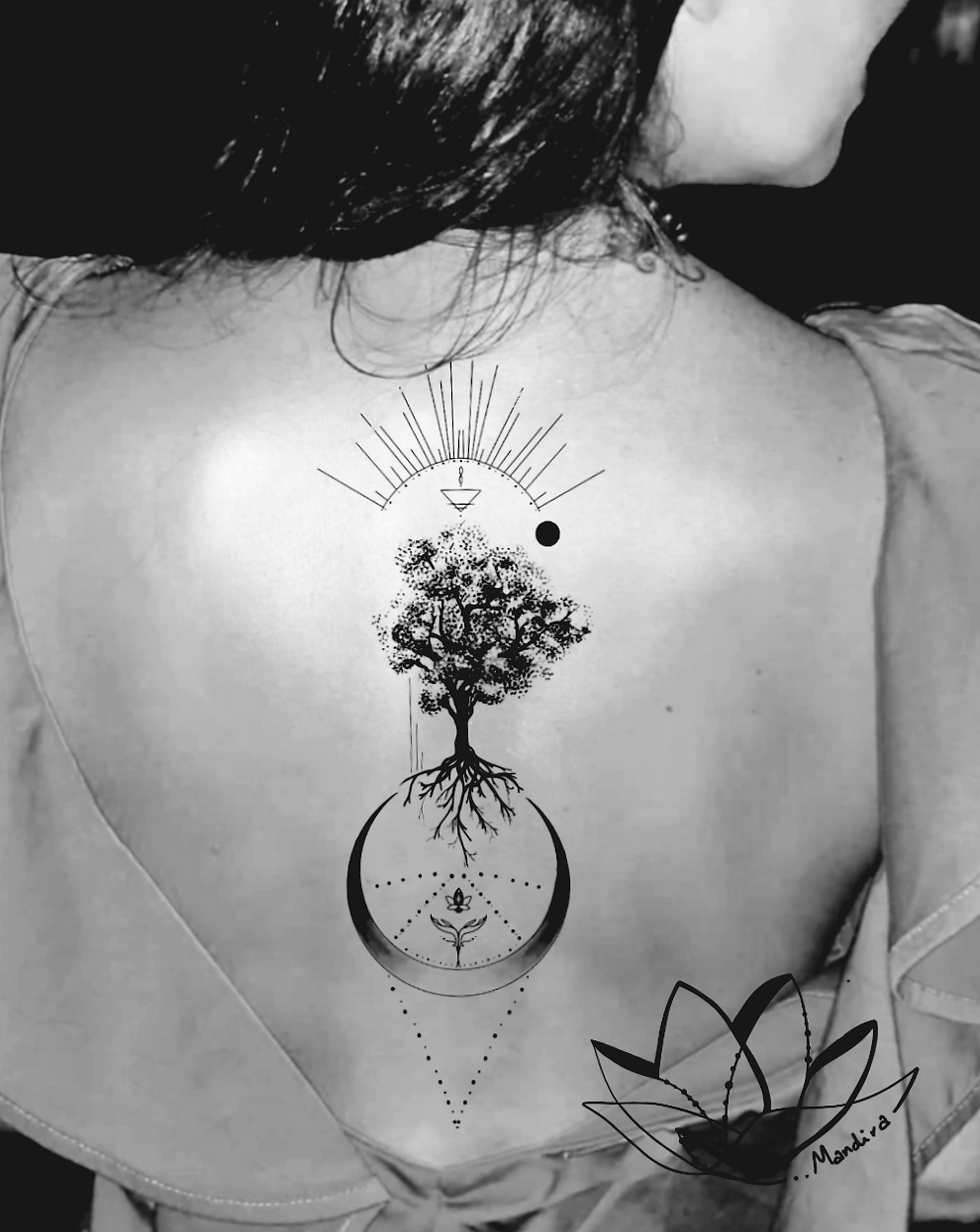 Female back photo, black and white, with a tattoo on her spine, a tree with roots and a big crescent moon, rays of light above the tree, triangles and other symbols that are part of a synthesis.