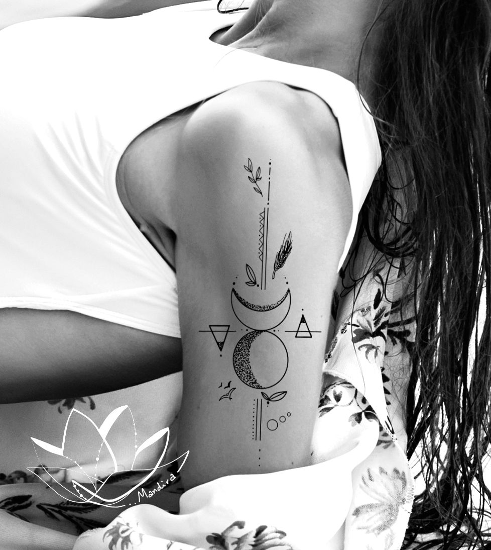 Photo of a woman with a white swimming suit and a floral shirt, focus on her upper arm tattoo with Full and Crescent moon, geometry elements half sleeve tattoo, lines, dots, elements of earth, wind and fire (triangles, birds, dots, branches)