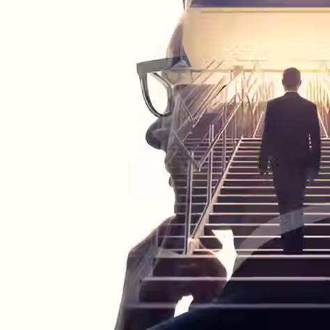 a head silhouette filled with a man in a suit climbing stairs towards a bright light, symbolizing ambition or progress.