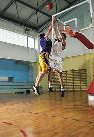 two young male athletes playng one on one basketball on a indoor basketball court