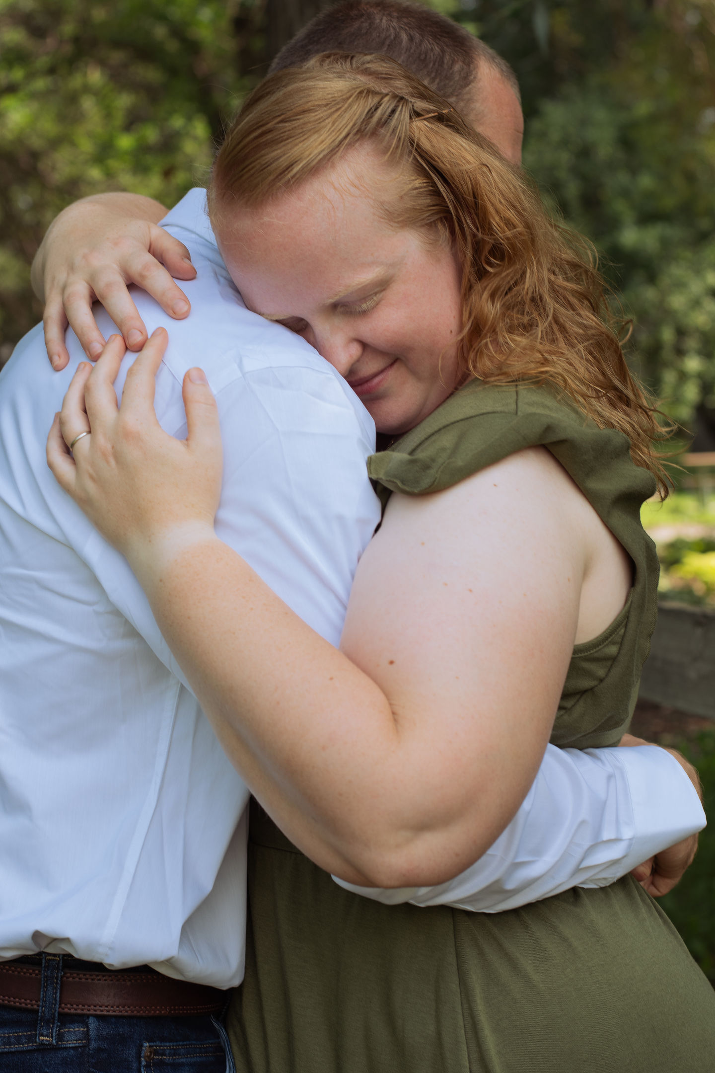 a woman with red hair is hugging a man in a white shirt
