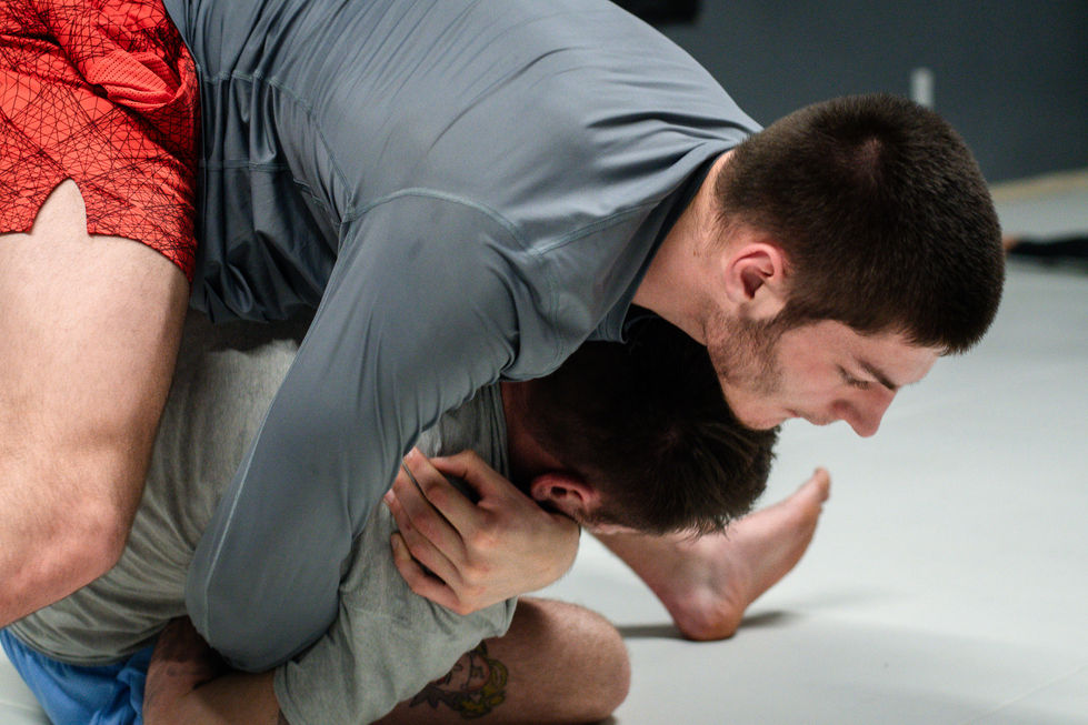 two men are wrestling and one has a tattoo on his leg