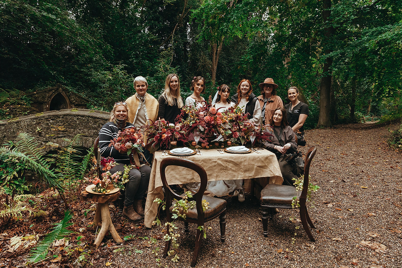 The styled photoshoot team standing in the woods behind the dressed table at Plas Newydd, Llangollen
