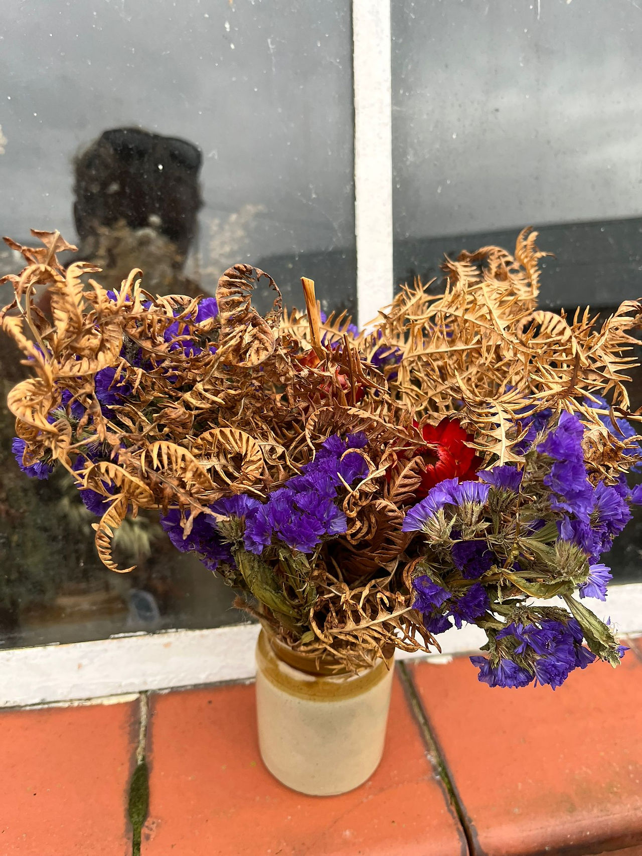 Dried flowers and bracken arranged in an earthenware vase