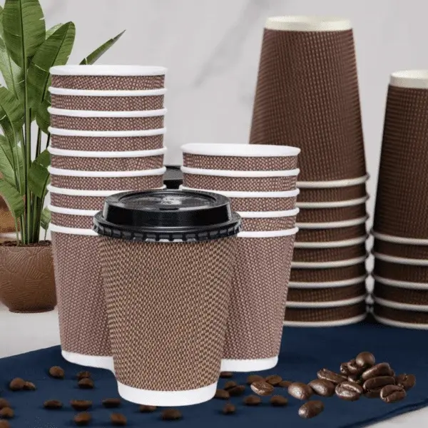 Mehrwegbecher und Einwegbecher. Gehäuft, mit Deckel und Kaffeebohnen verstreut.