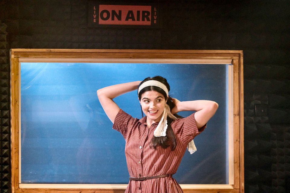 This Beautiful Future performance, a female actor stands in front of a recording booth, adjusting her pong tail