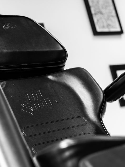 Schwarzer Tattoo-Stuhl, Grafik mit Rahmen, Studio-Hintergrund, bereit für Tätowierung.