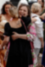 Two women embrace warmly, smiling, at an event. Friends and networking.