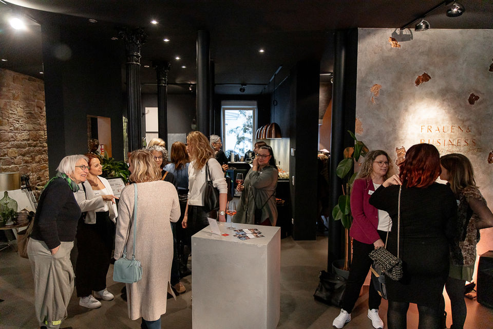 Frauen stehen zusammen in einem Raum, DAS NETZWERK von Frauen&Business. Gespräche und Interaktionen.
